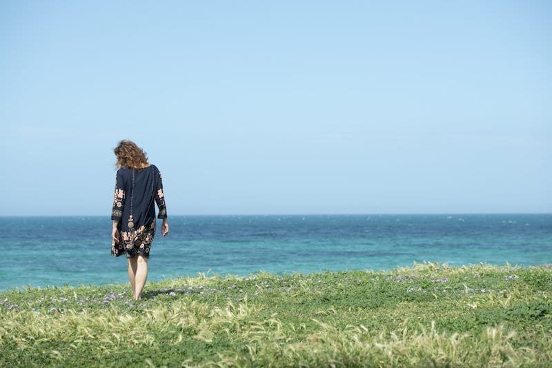 Midlife woman walks in a meadow by the sea in Pane e Pomodoro's beach in Bari (Apulia)