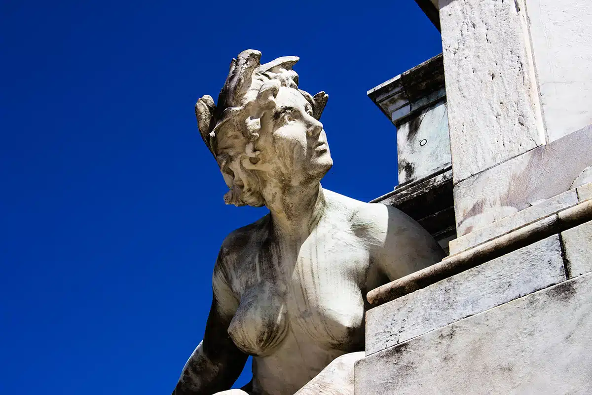 A photograph of a white female Renaissance statue against a stark blue sky.