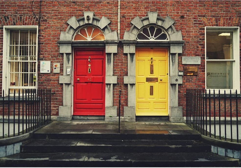 Red door and yellow door side by side on brick building, symbolizing choices in midlife transition.